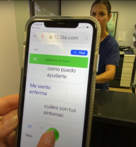 Iphone with guest using ILA app in Spanish. Nurse behind counter in background